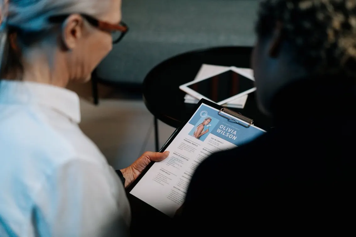 Woman seated at a table reviewing a resume