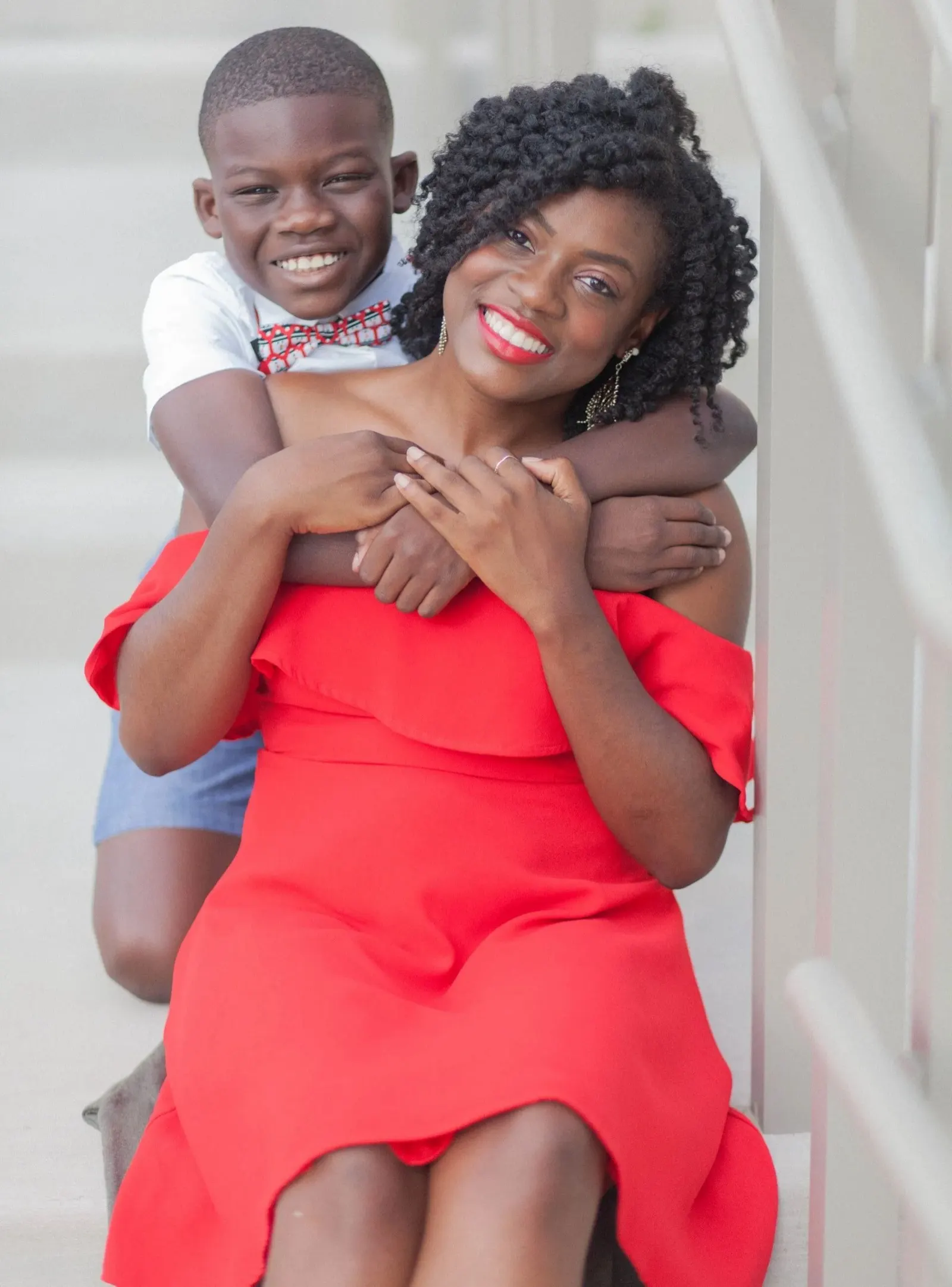 Smiling boy hugging his smiling mother from behind
