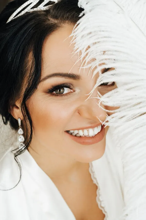 Smiling woman with a white feather beside her face